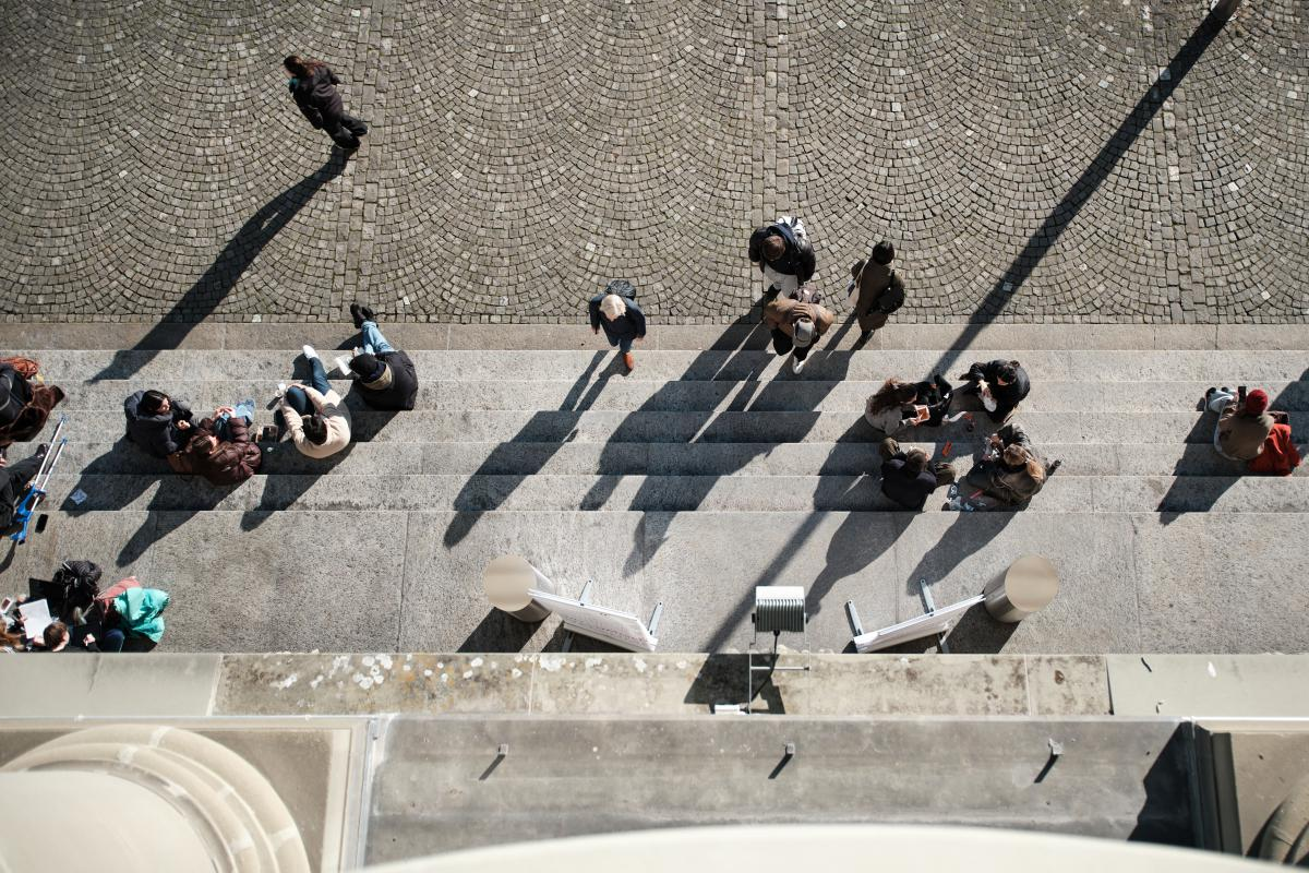 Hauptgebäude aus der Vogelperspektive von oben fotografiert. Auf den Treppen sitzen Personen.