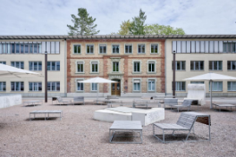 Uni Engehalde – Im Innenhof des Areals Tische und Bänke, aufgespannter Sonnenschirm. Gebäude im Hintergrund.