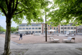 Uni Engehalde – Innenhof mit Sitzbänken, Tischen und aufgespannten Sonnenschirmen.