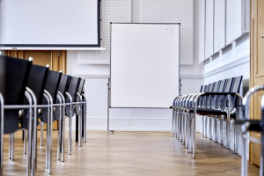 H6 – Sitzungszimmer 101 – schwarze Ledersessel sind rechts und links aufgereiht, im Hintergrund Magnettafel.