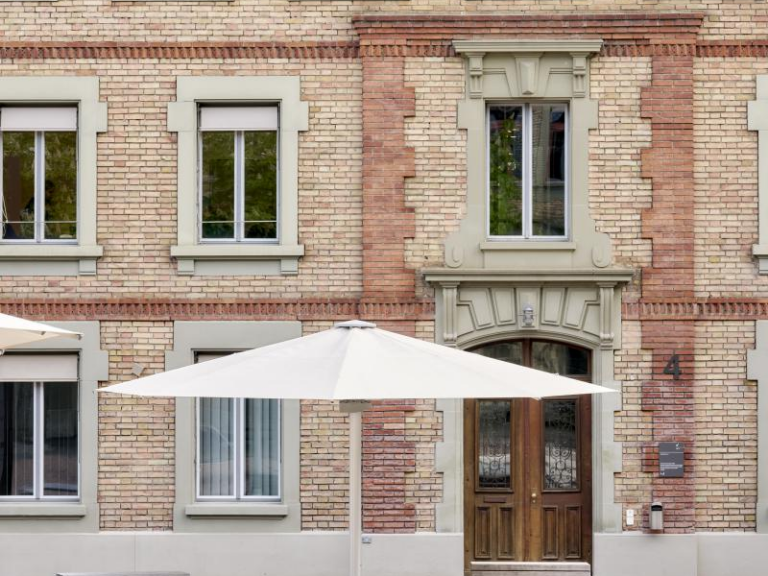 Uni Engehaldenstrasse 4 – Aussenbereich – Eingang, Sitzbänke, Tische, Sonnenschirme im Vordergrund