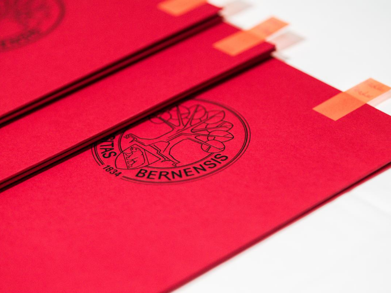 Dies academicus 2023 – rote Diplomrolle mit orangen Post-it markiert