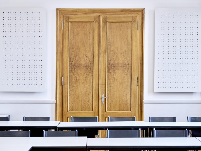 Sitzungszimmer; Eingangstüre mit Tischen und schwarzen Sesseln im Vordergrund